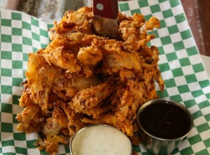 Fried onion ring loaf with two dipping sauces on checkered paper