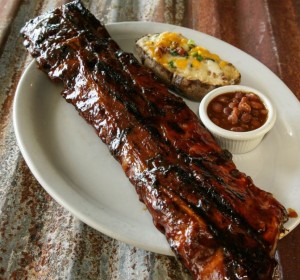 Barbecue ribs with a baked potato and baked beans on a plate