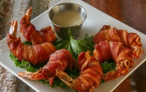 Plate of bacon-wrapped appetizers with a dipping sauce in the center
